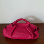 Pink handbag with a brand logo on a wooden surface