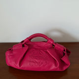 Pink handbag with a brand logo on a wooden surface