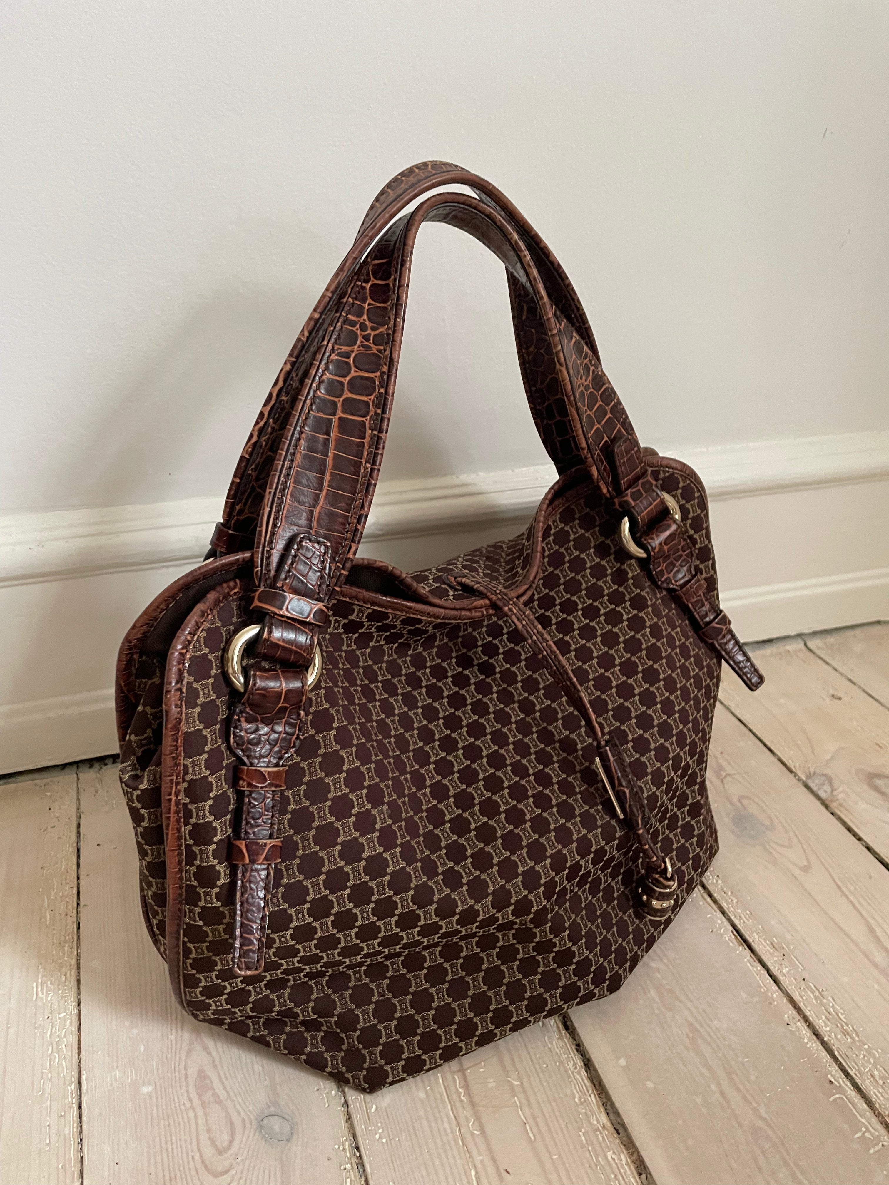 This is a Celine Macadam Bitter Sweet handbag, showcasing the brand's iconic macadam pattern. The bag features a combination of brown canvas and croc-embossed leather details, accentuated by gold-tone hardware.&nbsp;