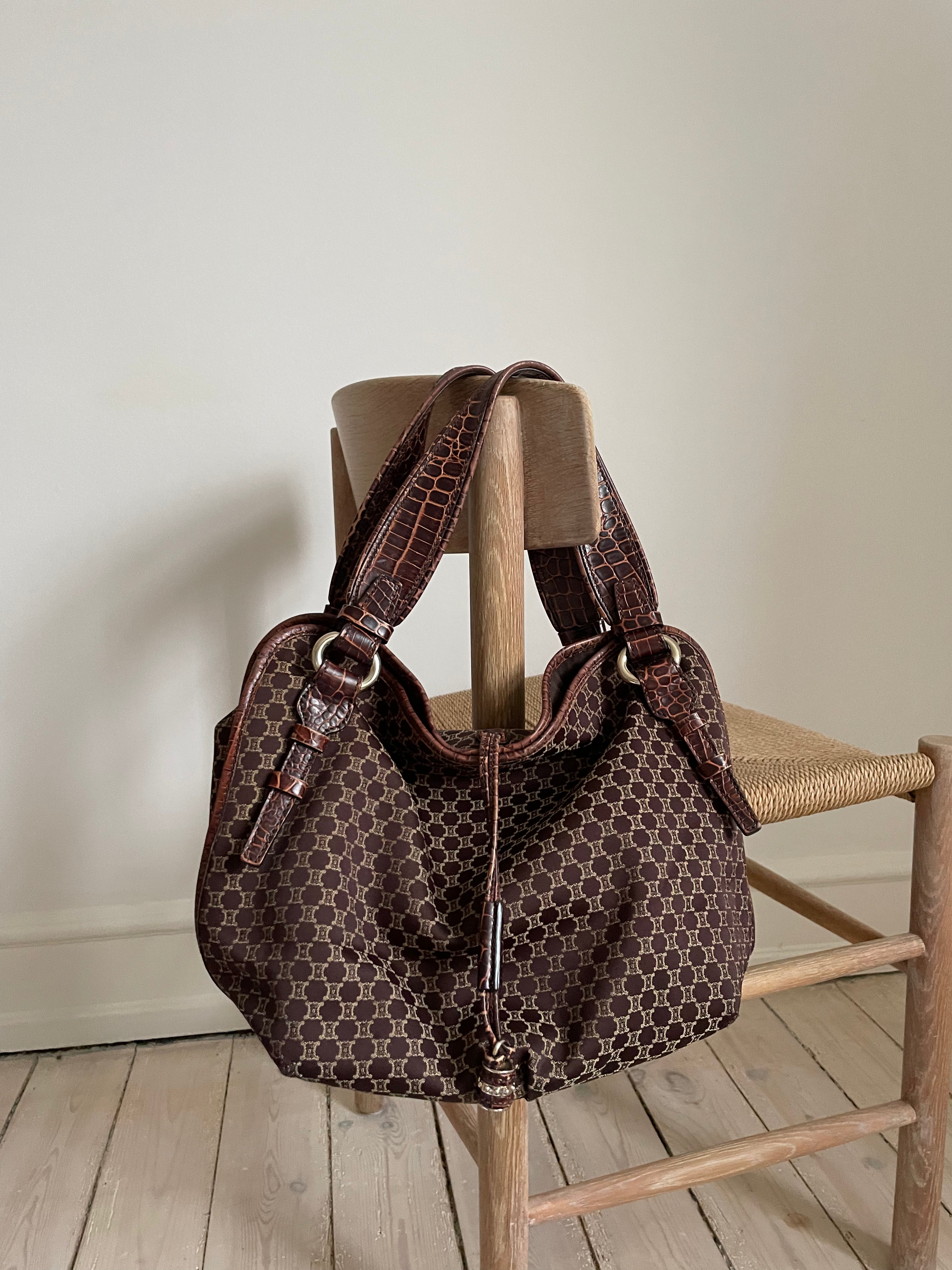 This is a Celine Macadam Bitter Sweet handbag, showcasing the brand's iconic macadam pattern. The bag features a combination of brown canvas and croc-embossed leather details, accentuated by gold-tone hardware.&nbsp;