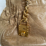 Miu Miu leather handbag. Crafted from matelassé calf leather, this handbag features luxurious lambskin and gold-tone hardware. It includes a front zip pocket, a top zip closure, and an interior slip pocket. The bag has a gold padlock charm.&nbsp;