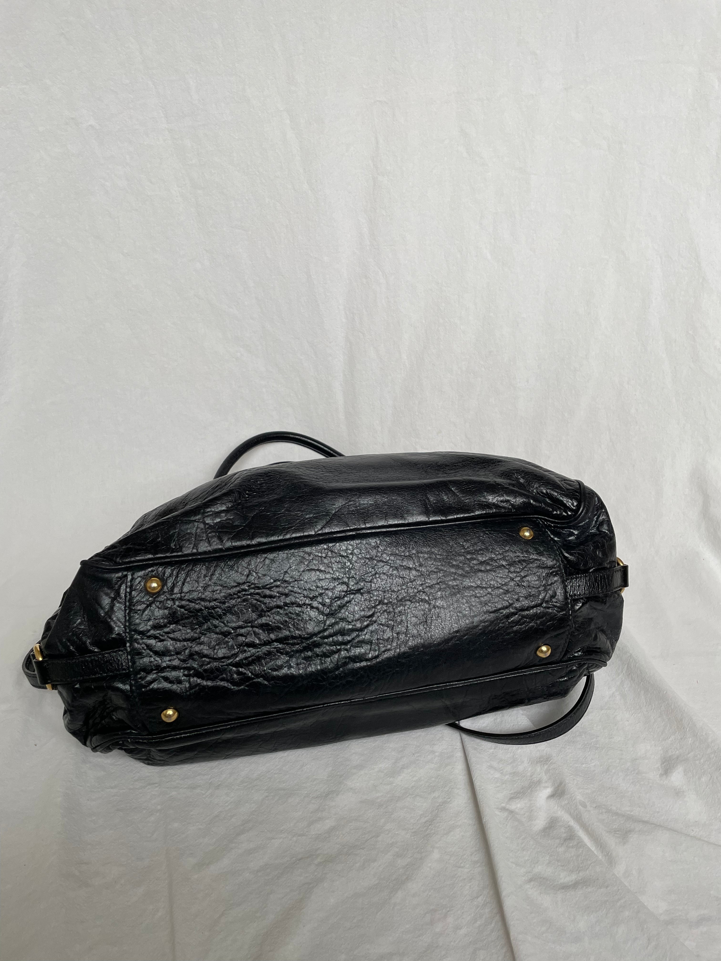 Miu Miu black nappa leather bag in a very good condition.

Crafted from nappa leather, this handbag features luxurious material and gold-tone hardware. It includes a front zip pocket, a top zip closure, and an interior slip pocket. The bag has a gold padlock charm.