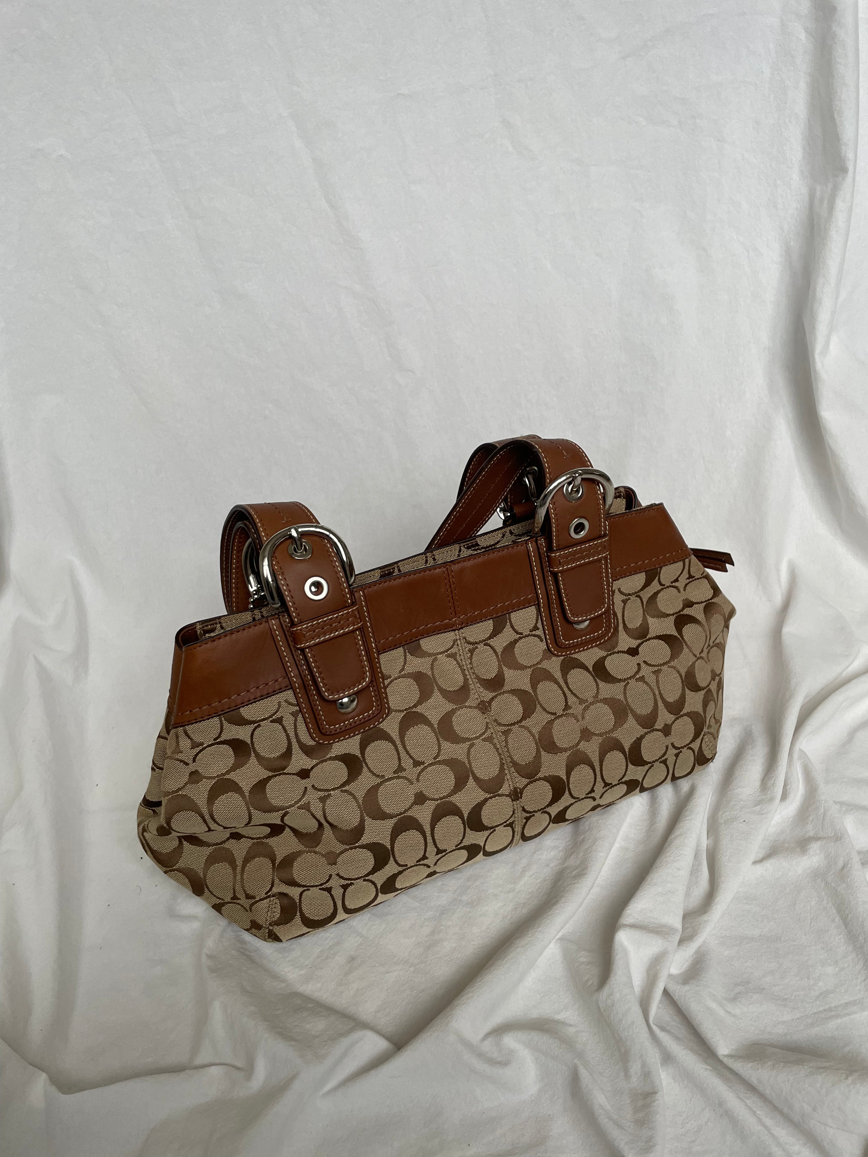 Beautiful Coach bag made from the brand’s signature canvas, with brown leather and silver hardware. Inside, there are three pockets—one with a zipper and two open.