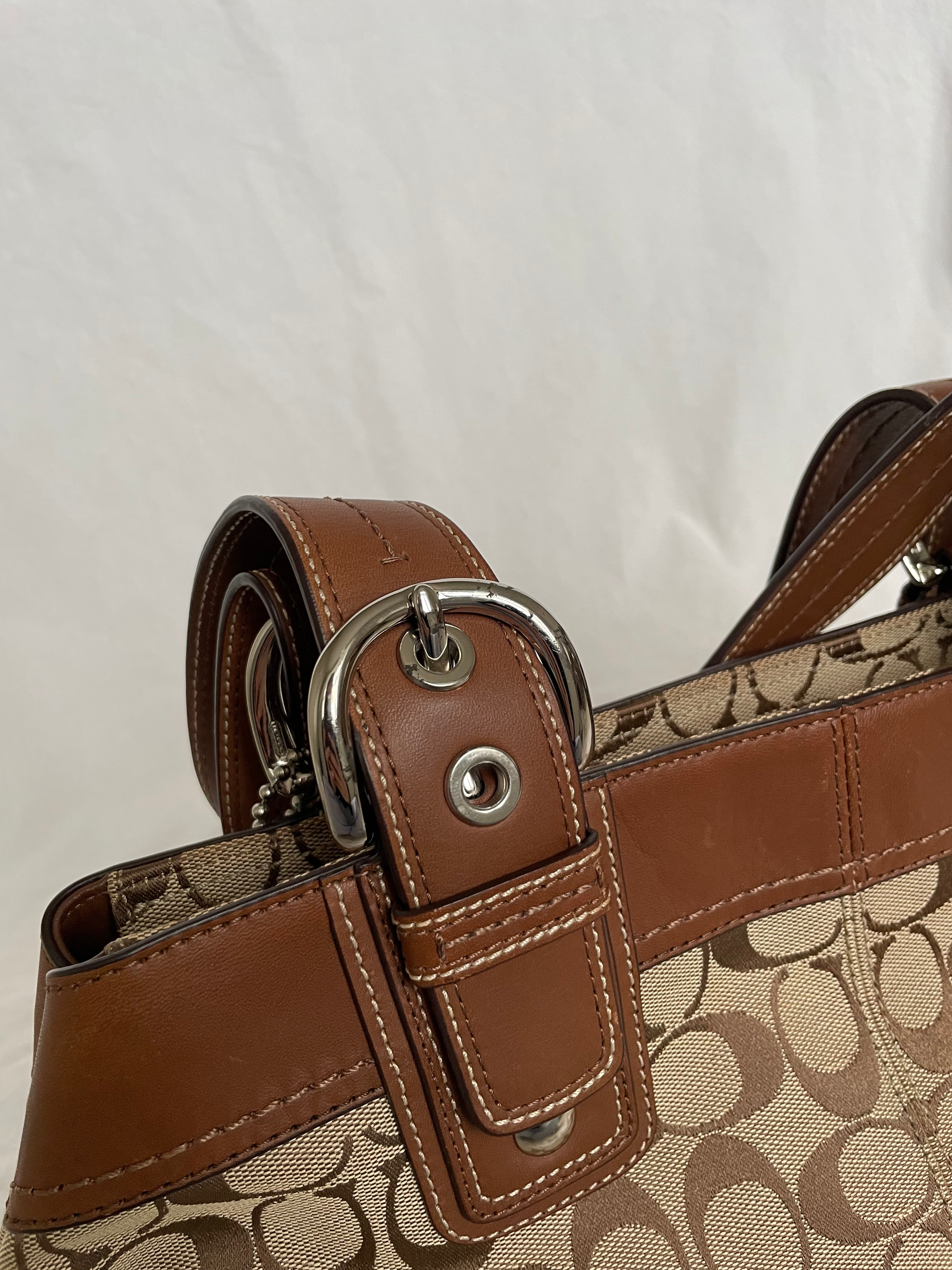 Beautiful Coach bag made from the brand’s signature canvas, with brown leather and silver hardware. Inside, there are three pockets—one with a zipper and two open.