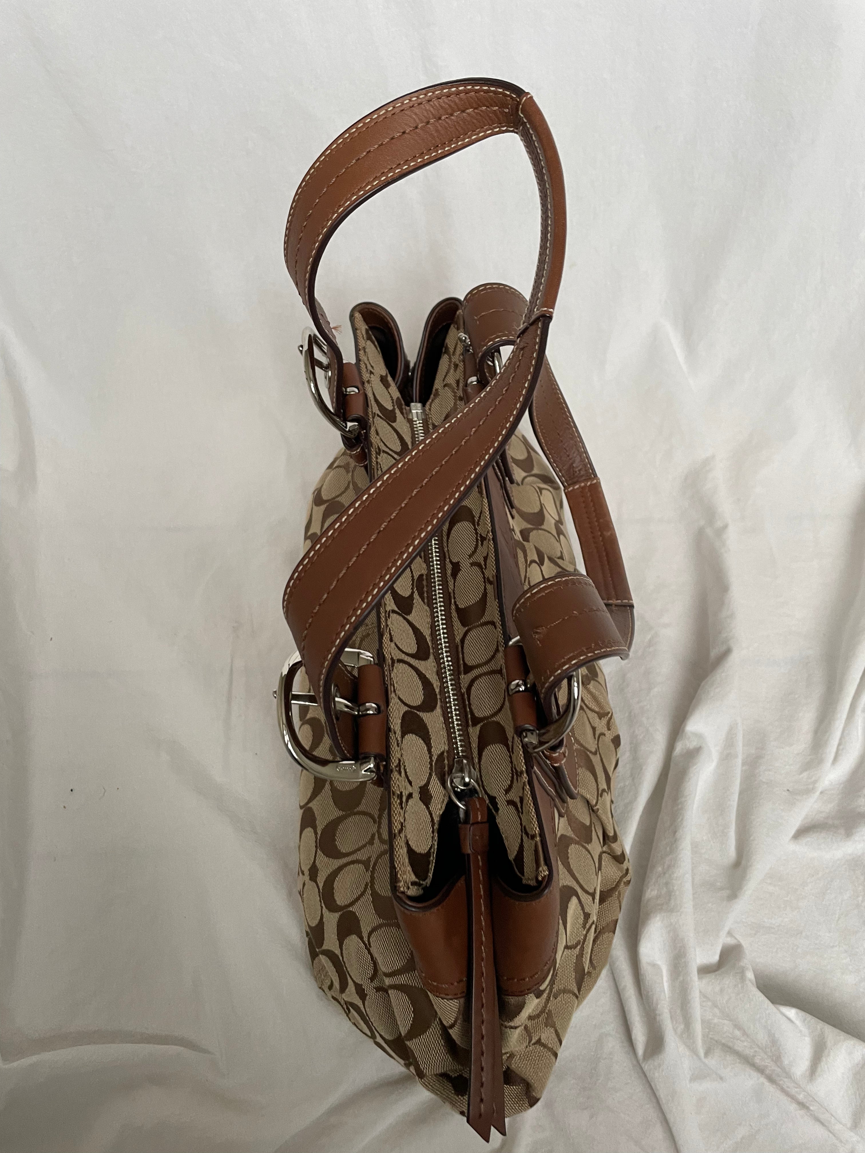 Beautiful Coach bag made from the brand’s signature canvas, with brown leather and silver hardware. Inside, there are three pockets—one with a zipper and two open.