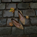 These vintage Coach ballet flats feature a pointed toe, lace-up details, and gold-tone eyelets along the edges. Crafted from beige suede with a smooth leather lining.