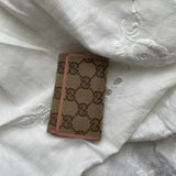 Gucci key wallet in iconic denim Gucci monogram and pink leather. The wallet shows signs of wear on the edges.