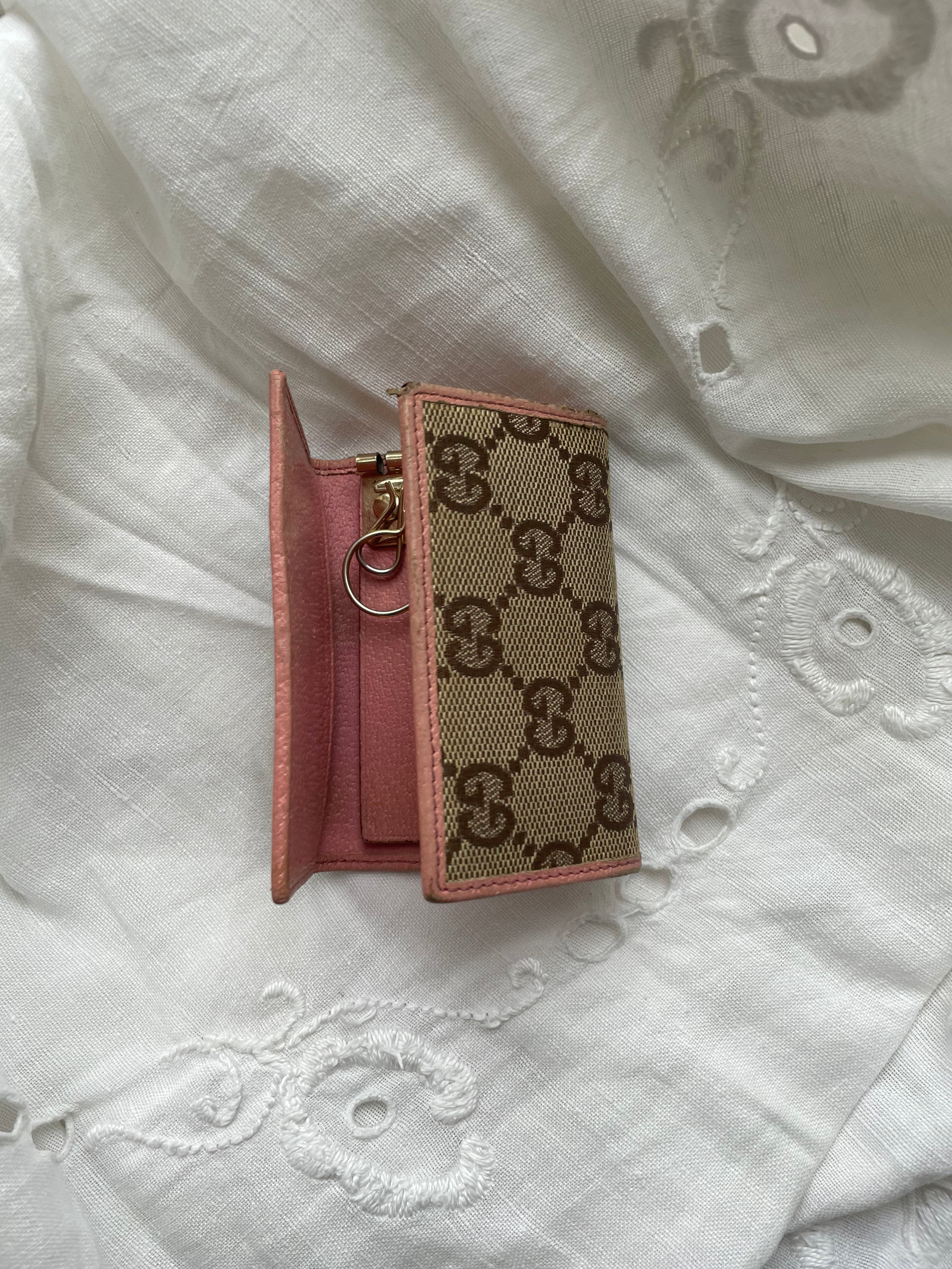 Gucci key wallet in iconic denim Gucci monogram and pink leather. The wallet shows signs of wear on the edges.