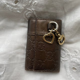 Gucci key wallet in brown leather with iconic monogram and a cute silver charm.