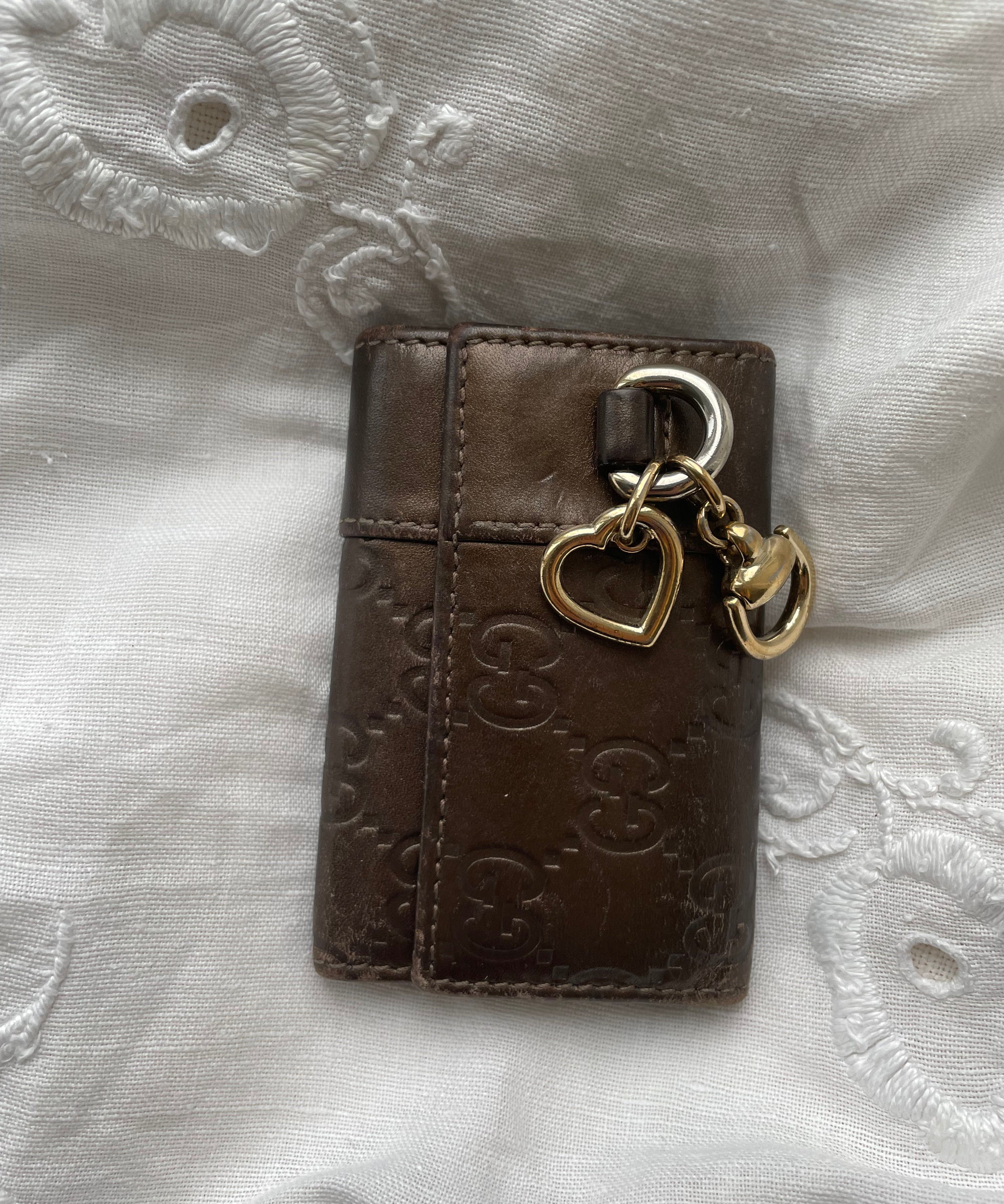 Gucci key wallet in brown leather with iconic monogram and a cute silver charm.
