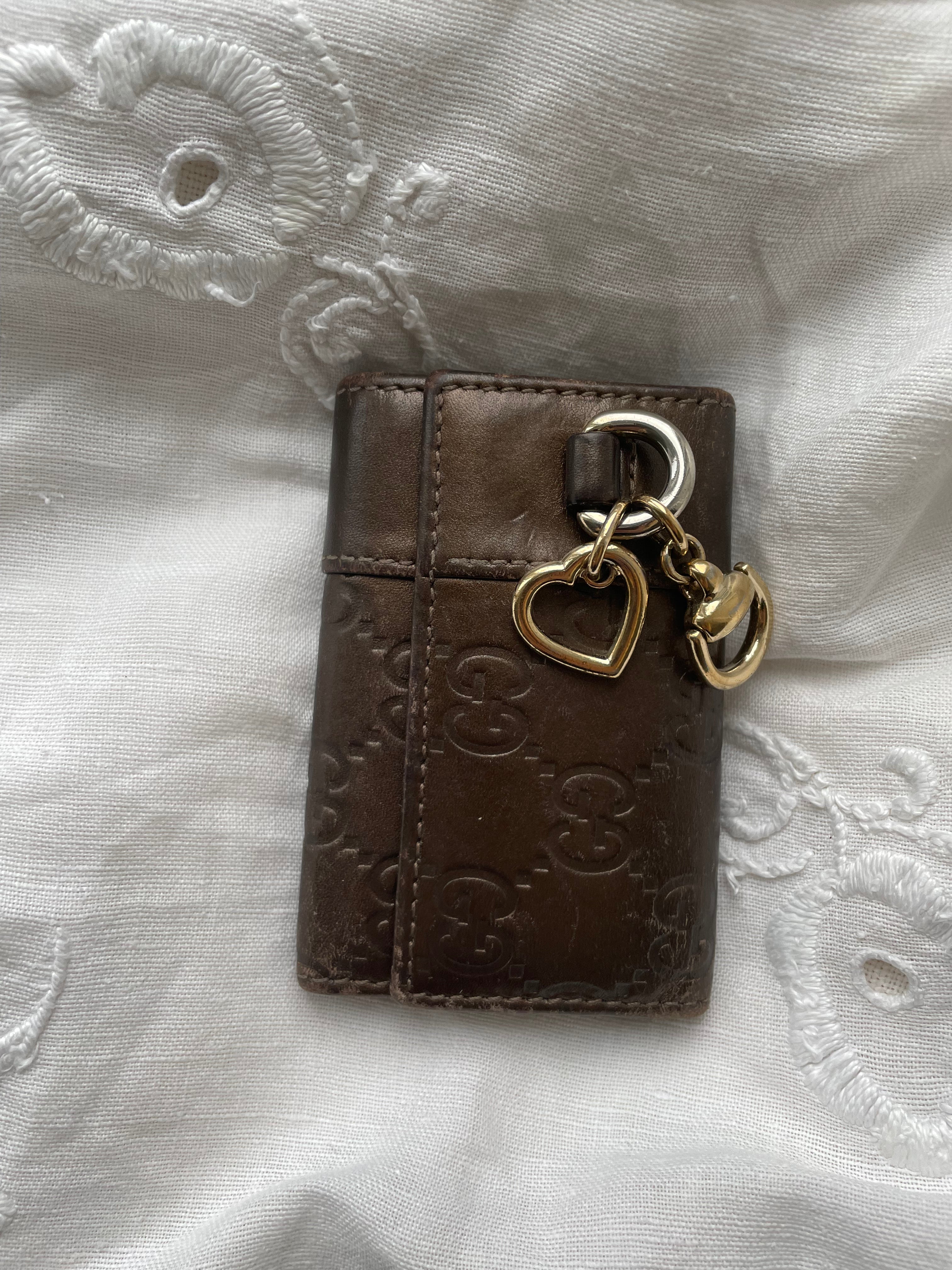 Gucci key wallet in brown leather with iconic monogram and a cute silver charm.