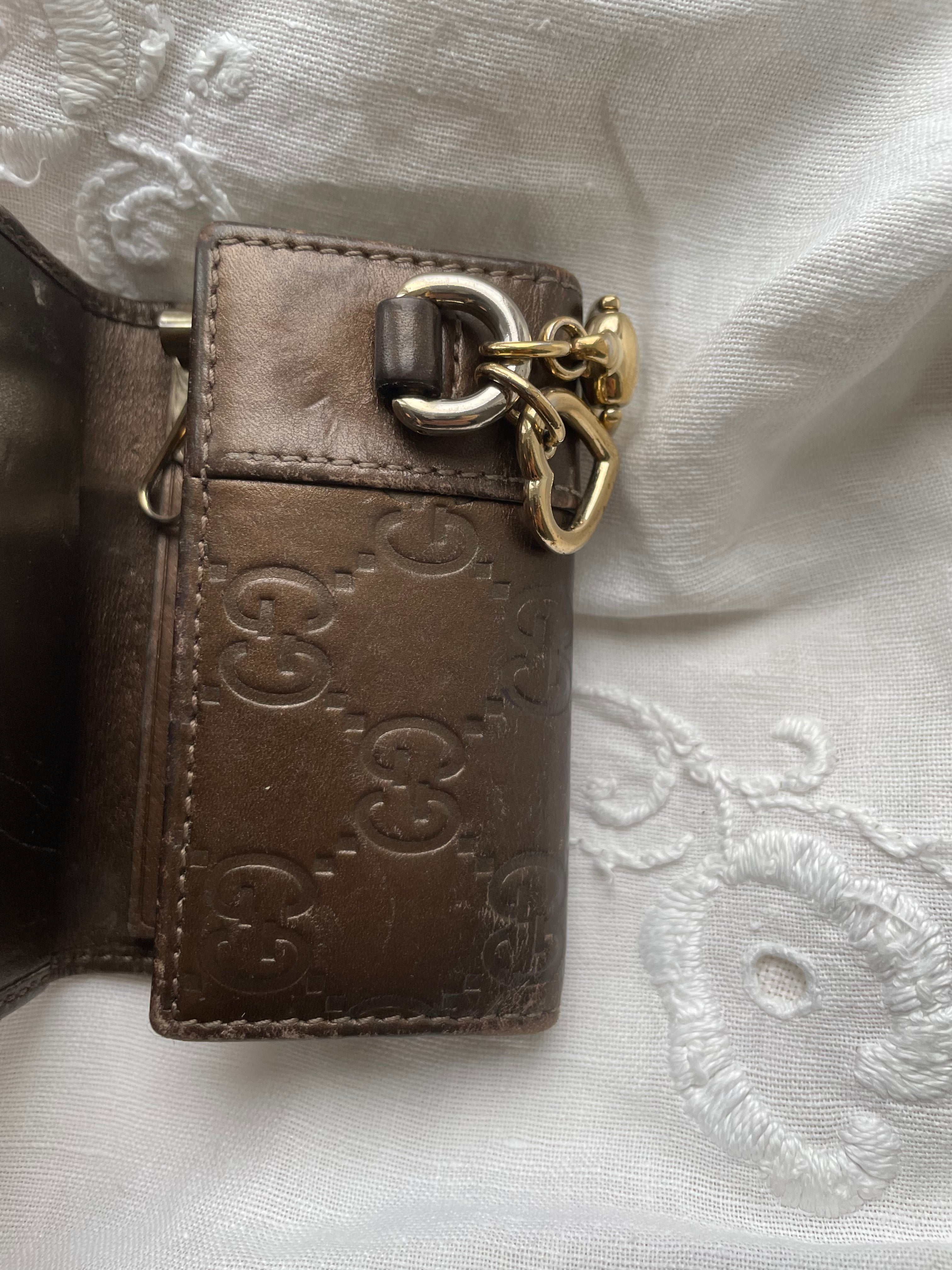 Gucci key wallet in brown leather with iconic monogram and a cute silver charm.