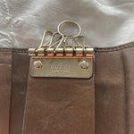 Gucci key wallet in brown leather with iconic monogram and a cute silver charm.