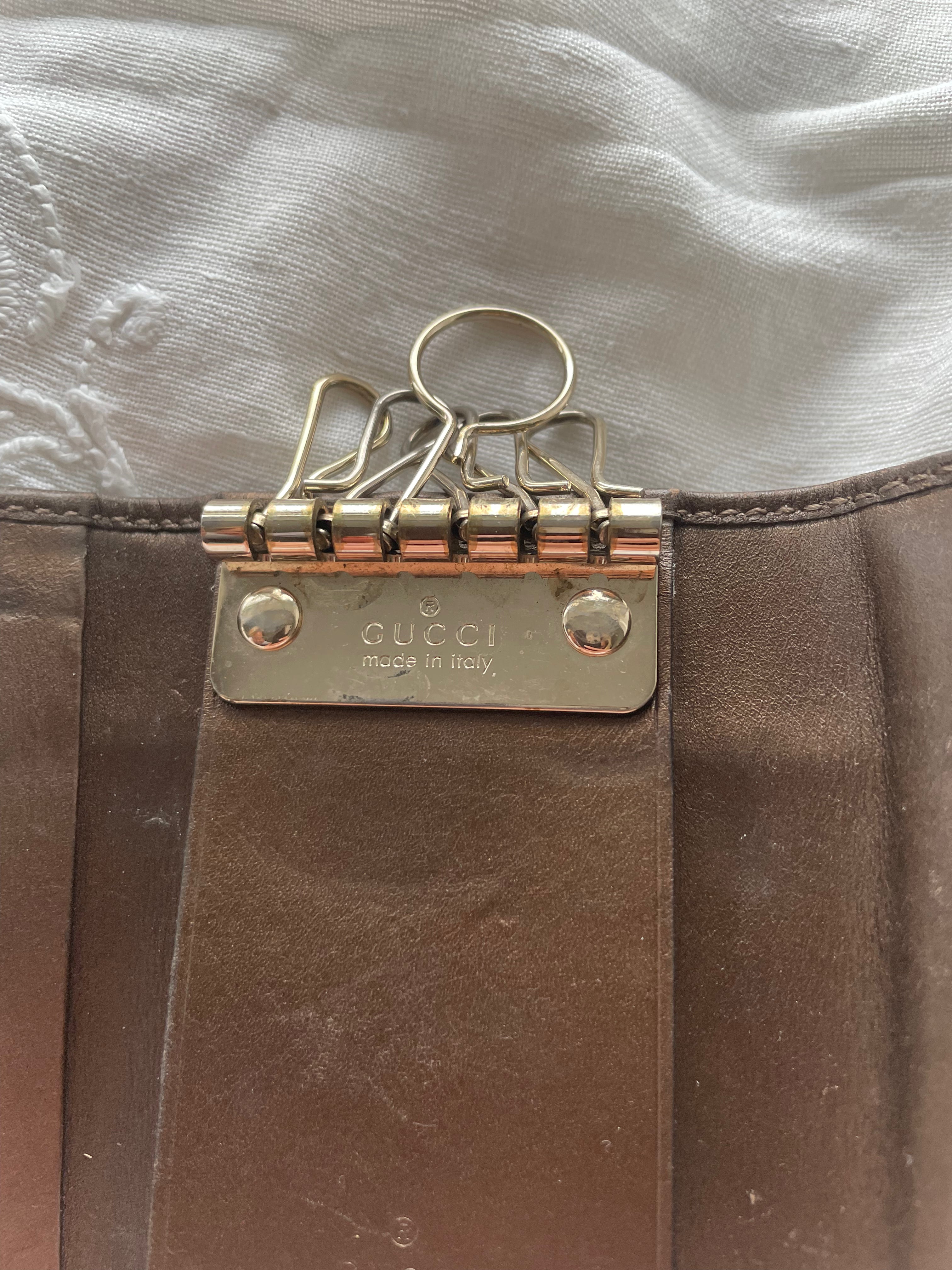 Gucci key wallet in brown leather with iconic monogram and a cute silver charm.