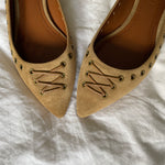 These vintage Coach ballet flats feature a pointed toe, lace-up details, and gold-tone eyelets along the edges. Crafted from beige suede with a smooth leather lining.