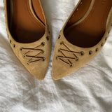 These vintage Coach ballet flats feature a pointed toe, lace-up details, and gold-tone eyelets along the edges. Crafted from beige suede with a smooth leather lining.