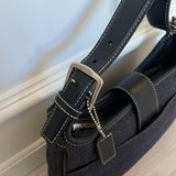 This vintage Coach bag from year 2000 is crafted from black leather and denim. It comes with an adjustable strap and magnetic closure, along with both an interior and exterior pocket. The bag is in great condition.