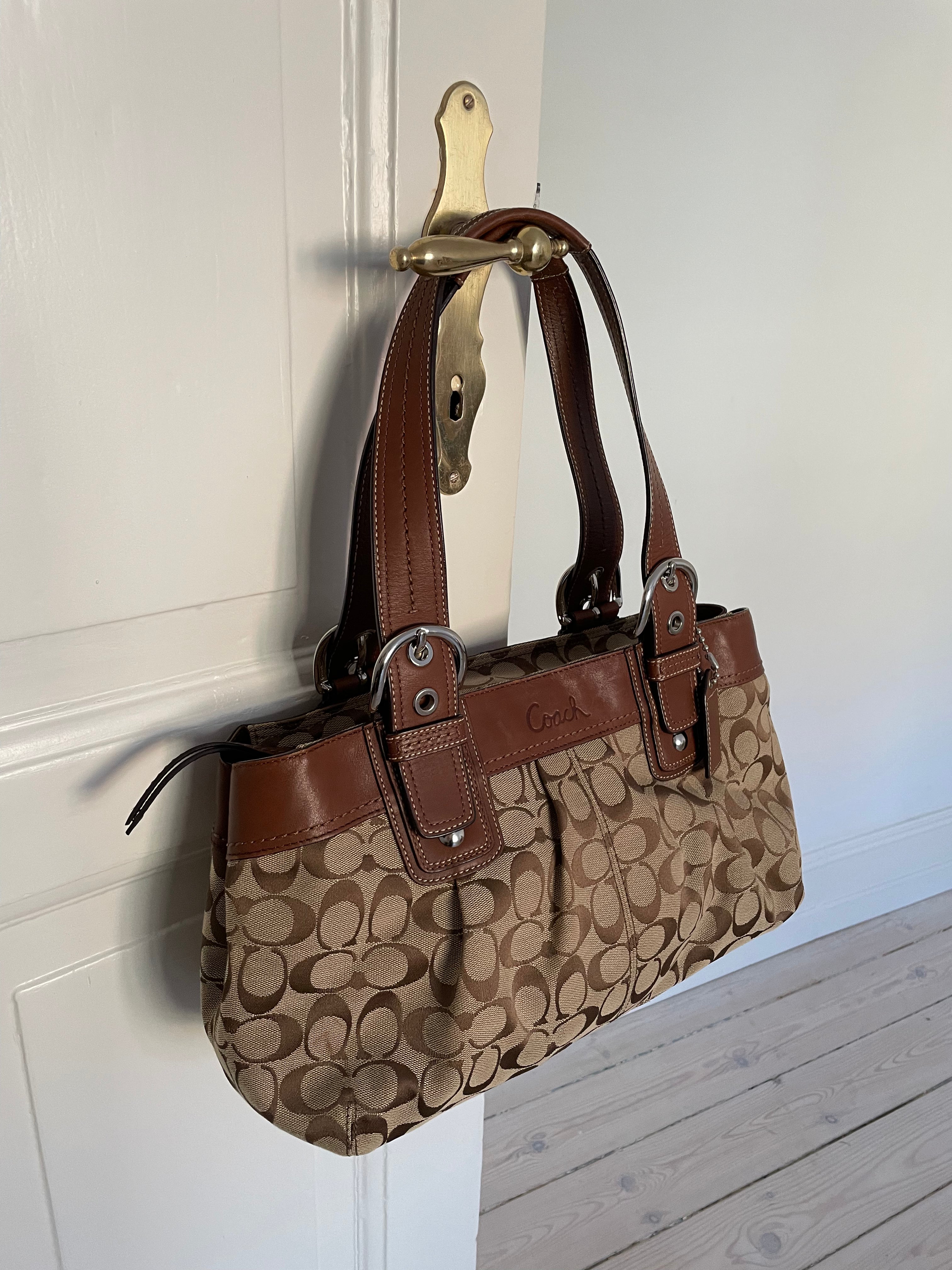 Beautiful Coach bag made from the brand’s signature canvas, with brown leather and silver hardware. Inside, there are three pockets—one with a zipper and two open.